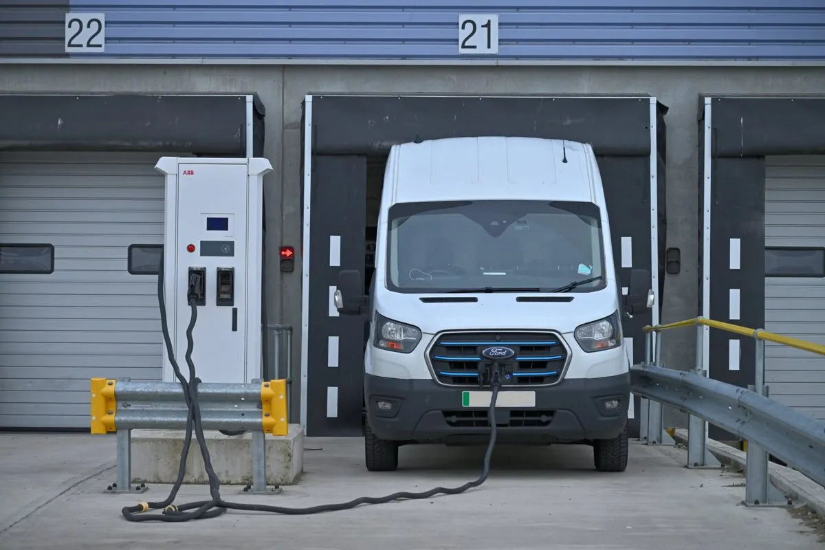White electric van charging from a high-power charger at a distribution centre loading bay
